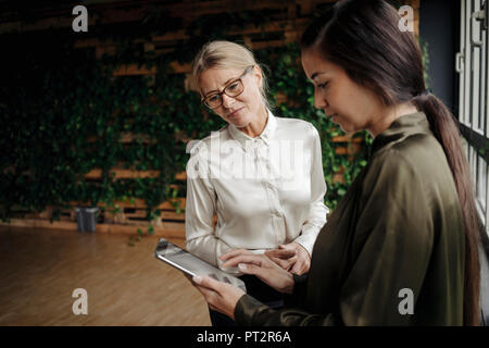 Due imprenditrici utilizzando tablet in ufficio Foto Stock