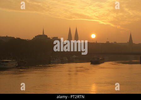 Sunrise nella città di Brema vista sul fiume Weser con una nave da trasporto barca andando sul Weser Foto Stock