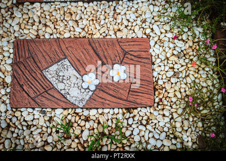 Vintage a piedi modo tile con ciottoli bianchi nel giardino. Blocco di pietra piastrella per il sentiero sulla ghiaia bianca di massa. Foto Stock