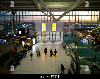 Il Terminal 5 di Londra Heathrow Airport a sunrise come visto dalla balaustra con i viaggiatori e area di attesa Foto Stock