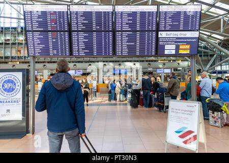 Amburgo / Germania - 28 settembre 2018: viaggiatori attende sotto un display di partenza per il check in, sull aeroporto di Amburgo Foto Stock