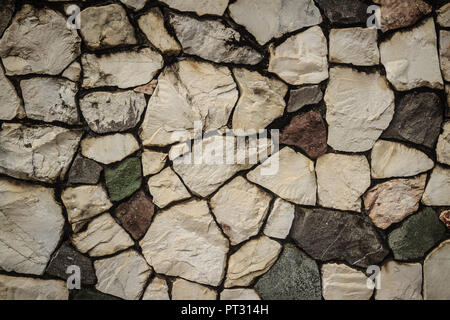 Natura Vintage parete di ciottoli in disorganizzato disegno di distribuzione dello sfondo. Parete di recinzione fatta di natura asimmetrica sfondo di pietra. Foto Stock