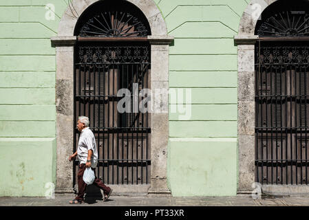 Uomo che cammina davanti a un edificio in stile coloniale di Merida, Messico Foto Stock