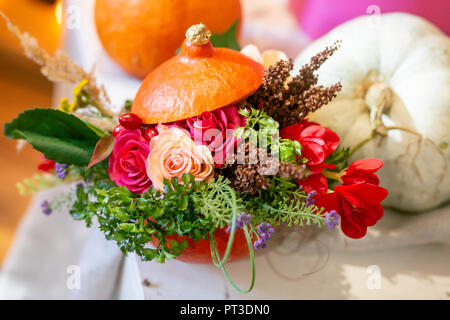 Come fare un ringraziamento centrotavola con grande zucca e bouquet di fiori. Foto Stock