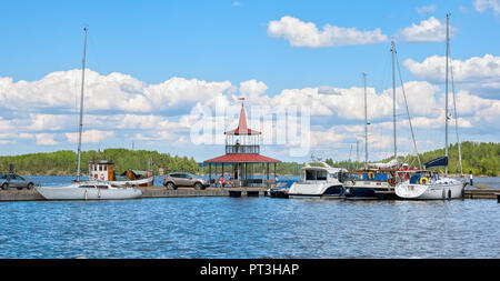 LAPPEENRANTA, Finlandia - 15 giugno 2016: persone sedersi sulle panchine vicino al padiglione sul piccolo molo con yacht e barche accanto al Lago Saimaa Foto Stock
