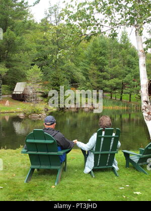 Coppia sposata godendo di azienda in verde sedie Adirondack. Foto Stock