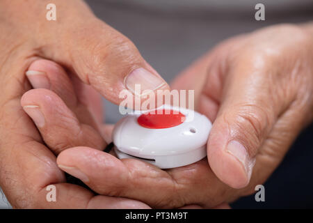 Close-up di una mano di un uomo premendo il pulsante di allarme di emergenza per Foto Stock