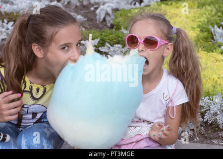 Due bambine di mangiare sulla strada un enorme dolce caramella di cotone. Foto Stock