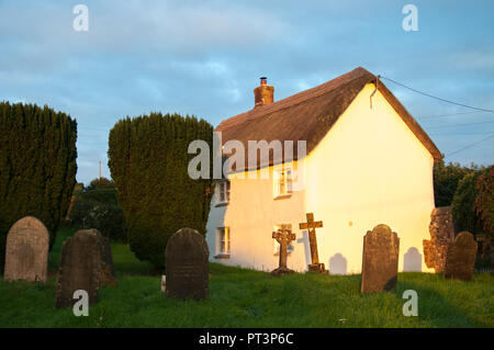 Cottage con il tetto di paglia accanto a un cimitero di Petrockstowe village, Devon, Southwest England Foto Stock