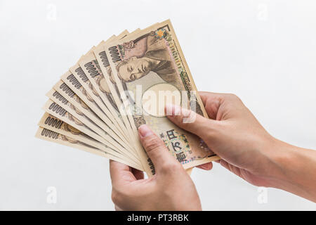 Imprenditrice dando denaro e tenendo 10.000 yen giapponese soldi in mano isolati su sfondo bianco, yen giapponese finanziaria e la concezione di business Foto Stock