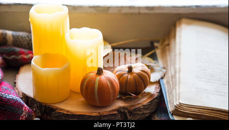 Caduta di decorazioni con candele e zucche con un libro e coperta, accogliente ancora vita Foto Stock