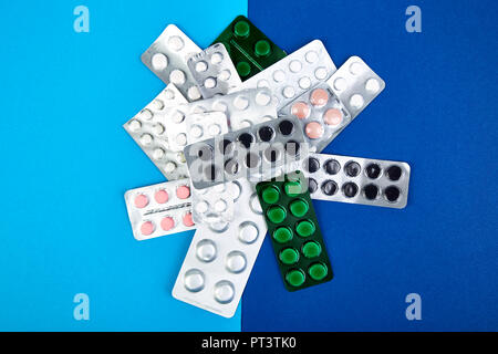 Pillole, compresse e blister su sfondo blu. Health care concetto. Lay piatto. Copia dello spazio. Foto Stock