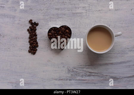 Tazza di caffè op e forma di cuore chicchi di caffè tostati su bianco tavola in legno rustico/ romantico still life food design/ mi piace il caffè Foto Stock
