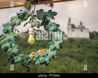 Spia gialla lampada in una ghirlanda di verde segno per una taverna di fronte Leopoldsberg (Vienna, Austria) Foto Stock