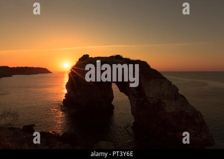 Europa Spagna Isole Baleari Maiorca costa Sud Santanyi - la roccia Es Pontas all alba con la riflessione della luce in acqua e sole Foto Stock