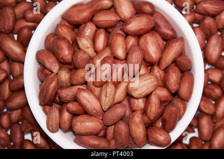 Arachidi in una ciotola bianco su uno sfondo di arachidi. Foto Stock