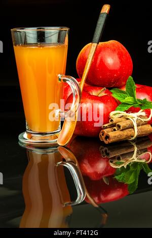 Freschi di succo di mela in un bicchiere. Raccolta dei frutti. Bevanda salutare. Mele sul tavolo della cucina. Produzione di succhi di frutta. Su uno sfondo nero Foto Stock