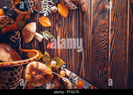 Funghi Porcini nel cestino con i frutti di bosco e i dadi su un tavolo di legno. Raccolto autunnale. Raccolto raccolto di caduta. Spazio Foto Stock