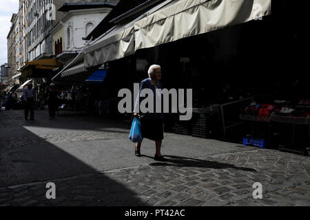 Una donna anziana sta portando una borsa da shopping come lei cammina al mercato Kapani a Salonicco, Grecia il 4 ottobre 2018. Foto Stock