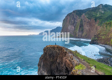 Persona su una scogliera guardando il sunrise, Faial, Santana comune, regione di Madera, Portogallo, Foto Stock