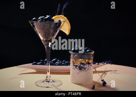 Coctail con bluberriy nella coppetta Martini sul tavolo di legno e backgrouns nero Foto Stock