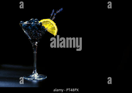 Cocktail con bluberriy nella coppetta Martini isolati su sfondo nero Foto Stock