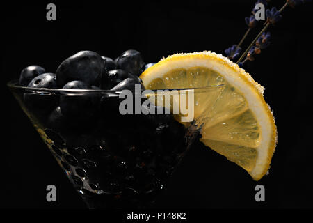 Cocktail con bluberriy nella coppetta Martini isolati su sfondo nero Foto Stock