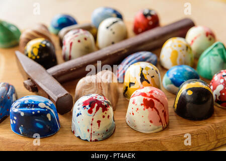 Assortimento di cioccolato artigianale bomboni e un martello di cioccolato su un legno di quercia vassoio. Foto Stock