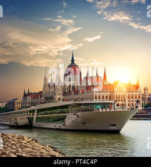 Tramonto sul Parlamento ungherese e imbarcazione turistica sul fiume Danubio Foto Stock