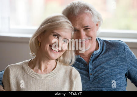 Headshot ritratto di felice di mezza età coppia romantica dating in posa in interni, sorridente pensionati vecchia famiglia abbracciando guardando la telecamera, amorevole senior ma Foto Stock