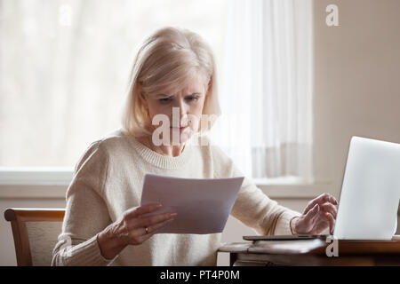 Grave frustrato di mezza età donna senior preoccupato leggendo le cattive notizie in carta formato lettera documento, ha sottolineato sconvolto coppia lady turbato con le bollette domestiche Foto Stock