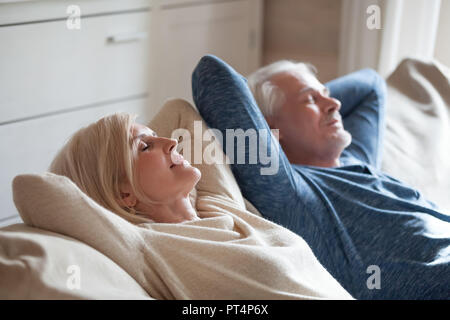 Calma senior coppia matura rilassante sui morbidi divani confortevoli avente nap diurne insieme spensierato di mezza età antica famiglia respirando aria fresca godendo Foto Stock