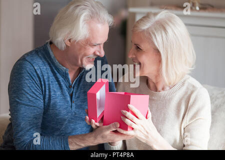 Excited donna senior apertura scatola regalo ricevere presente da hus Foto Stock