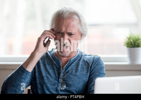 Arrabbiato senior uomo sostenendo parlando al telefono lamenta il problema Foto Stock