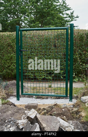 Giardino la costruzione di installazione di un nuovo metallo verde porta d ingresso e una recinzione intorno al perimetro di protezione e sicurezza con lavori di sterro nella foregroun Foto Stock