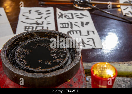 Strumenti e materiali di consumo utilizzati nell apprendimento di caratteri cinesi tradizionali calligraphy sul piano portapaziente in aula. Foto Stock