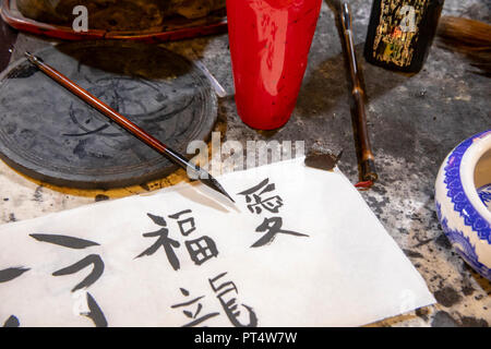 Strumenti e materiali di consumo utilizzati nell apprendimento di caratteri cinesi tradizionali calligraphy sul piano portapaziente in aula. Foto Stock