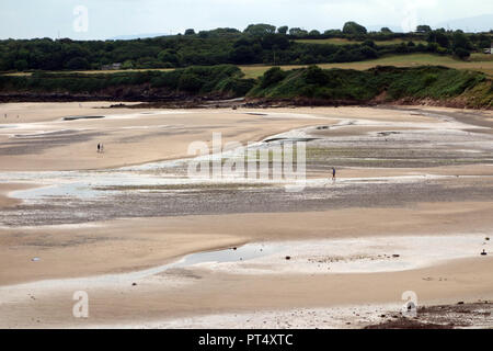 La gente camminare sulla sabbia di Traeth Lligwy Beach sull'Isola di Anglesey sentiero costiero, Wales, Regno Unito. Foto Stock