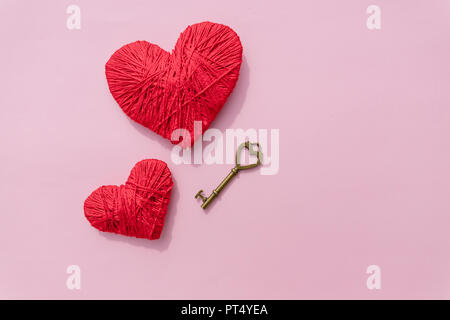 La chiave per l'amore, cuore rosso.filati colorati cuore isolato su sfondo rosa.Il giorno di San Valentino cuore, amore .dating concetto. Spazio di copia Foto Stock