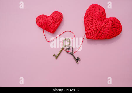 Decorazione cuore rosso e piccola chiave di metallo contro sfondo rosa.festosa immagine romantica per il giorno di San Valentino. Copia dello spazio. Vacanze cartolina su amore e sentimenti. Foto Stock