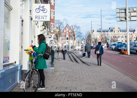 AMSTERDAM, PAESI BASSI - Marzo 2018: giovane donna a un noleggio bike shop nel vecchio quartiere centrale di Amsterdam Foto Stock