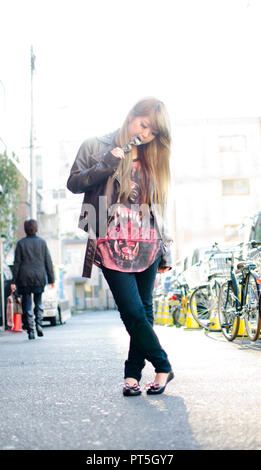 Ragazza giapponese pone sulla strada in Shibuya, Giappone. Shibuya è una città che i giovani appendere fuori e andare a fare shopping. Foto Stock