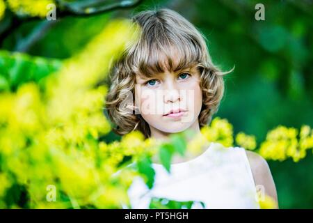 Ritratto di giovane ragazzo con fiori di colore giallo in primo piano. Foto Stock