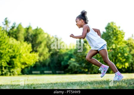 Bambina in esecuzione nel parco, sorridente. Foto Stock