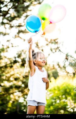 Ragazza con mazzo di palloncini in park. Foto Stock