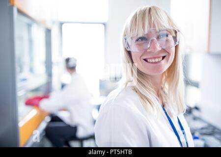 Medico donna indossa occhiali protettivi e sorridente. Foto Stock