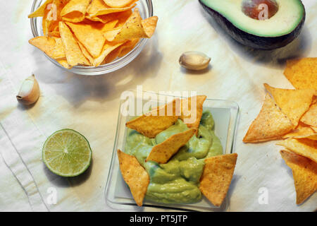 Triangolare di nachos chips in guacomole salsa a base di calce, aglio e avocado. Foto Stock