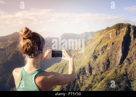 La ragazza è di scattare foto in raggi di alba Foto Stock