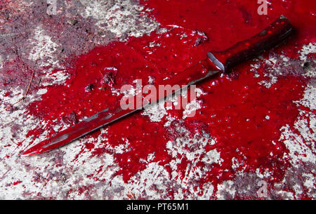 Immagine concettuale di un coltello affilato con il sangue su di essa appoggiato su un pavimento di calcestruzzo. Concetto foto di omicidio e la criminalità Foto Stock