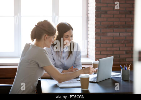 Le colleghe che lavorano insieme con il computer portatile utilizzando corporate s Foto Stock